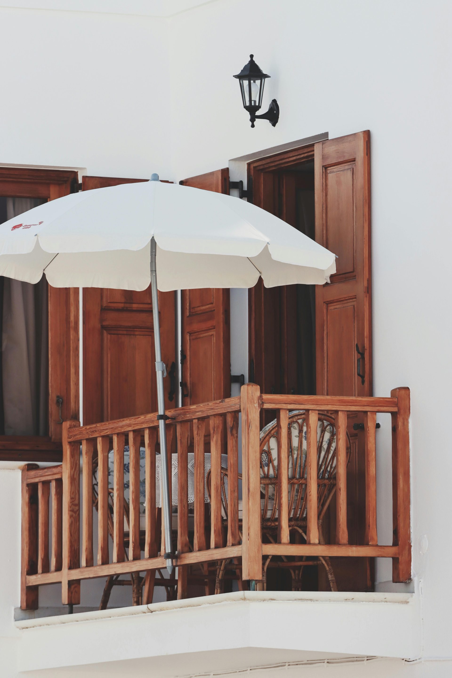 A cozy balcony in Naxos, Greece featuring wooden elements and a white parasol, exuding classic Aegean style.